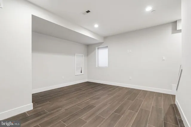 an empty room with wooden floor and window