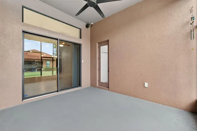 a view of an empty room with wooden floor ceiling fan