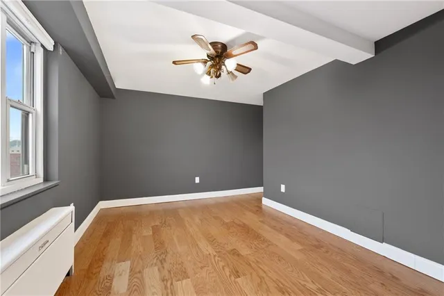a view of an empty room with window and wooden floor
