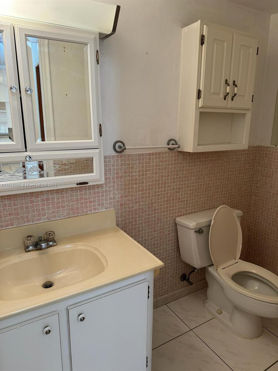 1747 Rodman Street, Unit 203 Hollywood, FL 33020 - Photo 7 of 16 a bathroom with a sink a toilet and a mirror