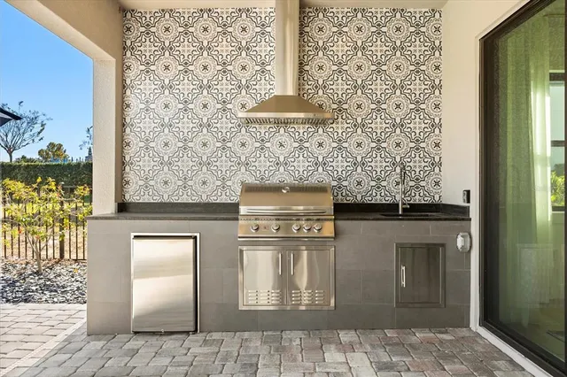 a view of a patio with dining table and chairs with potted plants and a barbeque