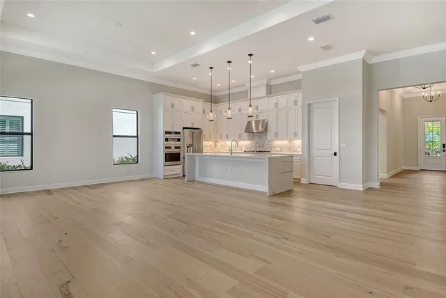a view of an empty room with kitchen and window