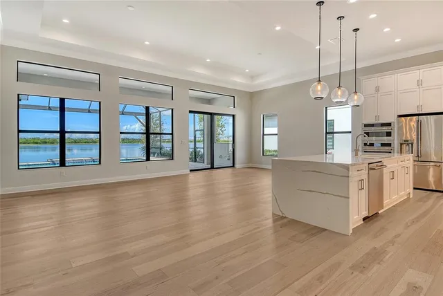 a view of an empty room with kitchen and window