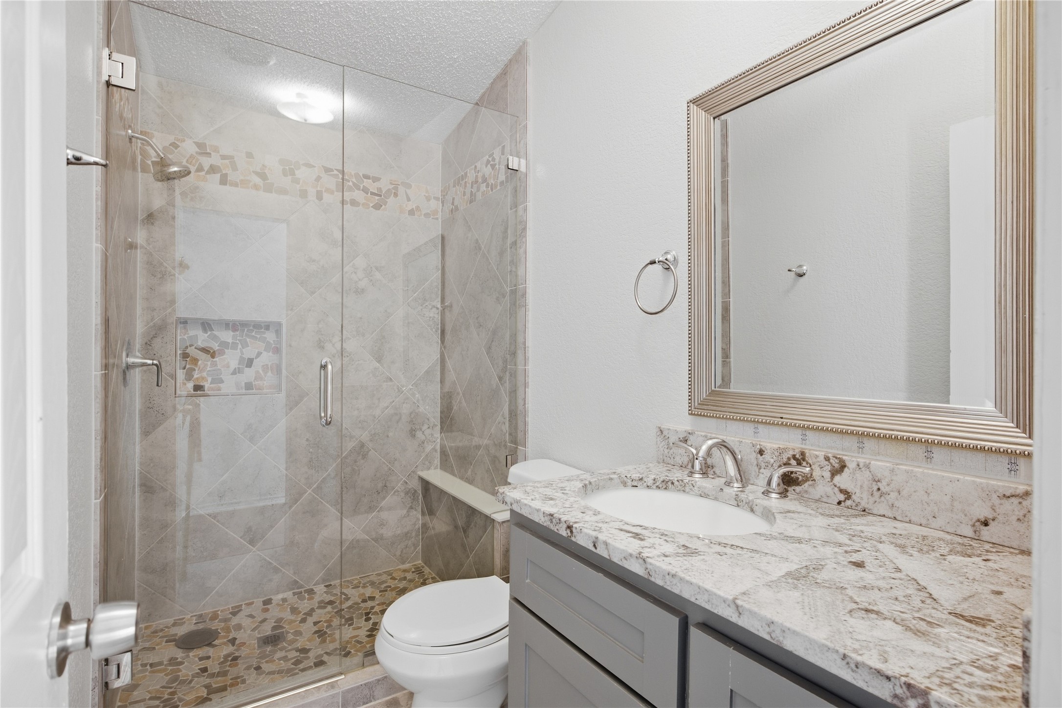 2709 County Road 463 Elgin, TX 78621 - Photo 21 of 32 A framed mirror sits above a granite vanity alongside a glass-enclosed walk-in shower.