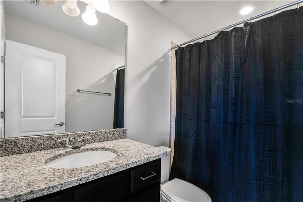 a bathroom with a granite countertop sink vanity mirror and toilet