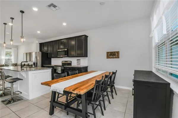 a kitchen with stainless steel appliances kitchen island granite countertop a dining table chairs microwave and sink