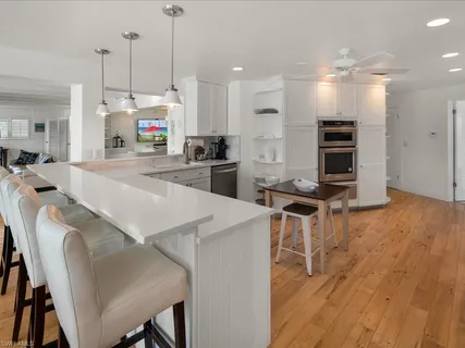 a open kitchen with stainless steel appliances kitchen island granite countertop a stove a refrigerator a oven a sink with island chairs and wooden floor