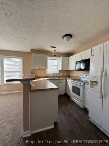 a kitchen with granite countertop a sink cabinets stainless steel appliances and a window