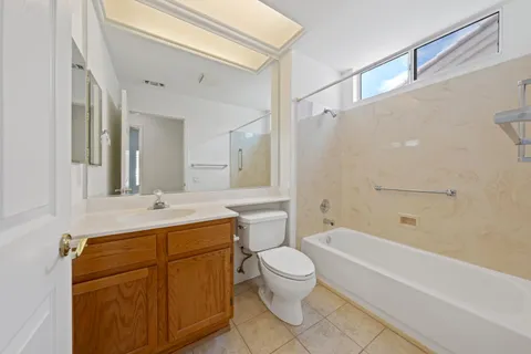 a bathroom with a granite countertop bathtub shower sink mirror vanity and toilet