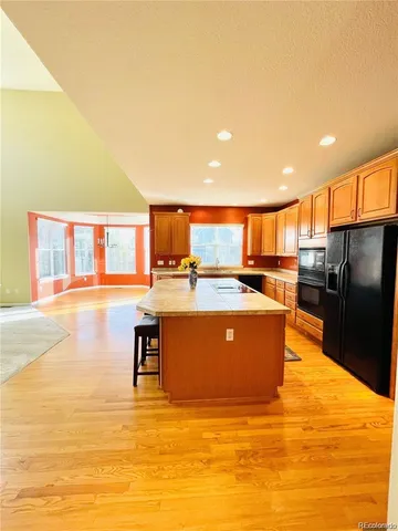 a kitchen with stainless steel appliances granite countertop a refrigerator a stove and a sink with wooden floor