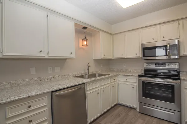 a kitchen with stainless steel appliances granite countertop white cabinets and a sink