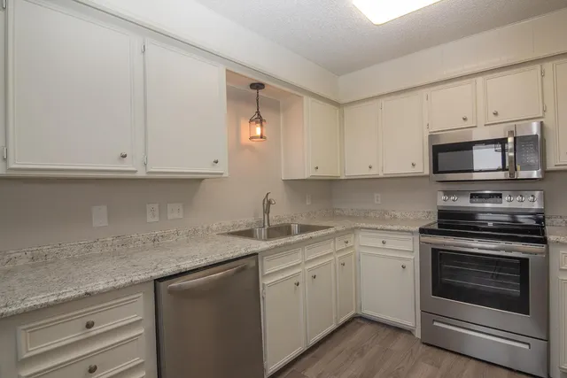 a kitchen with stainless steel appliances granite countertop white cabinets and a sink