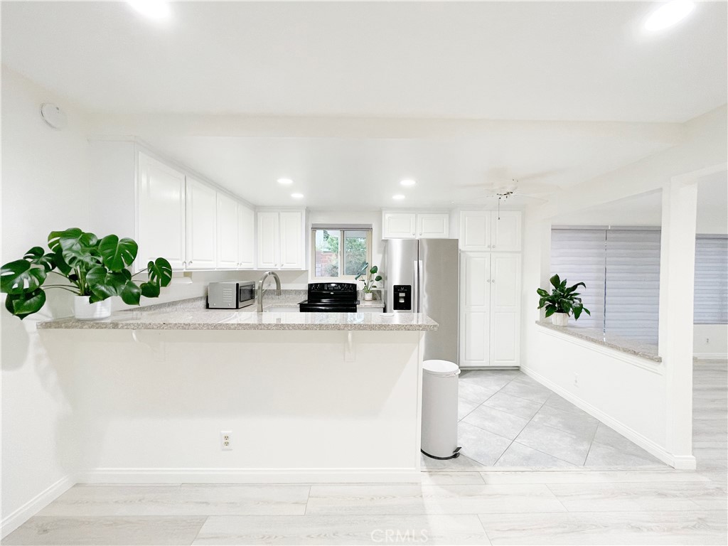 2052 South June Place Anaheim, CA 92802 - Photo 3 of 12 a white kitchen with stainless steel appliances granite countertop a refrigerator a sink and white cabinets
