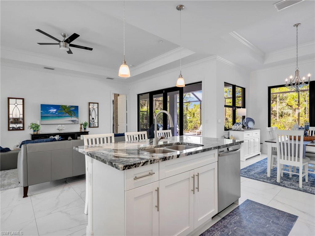 2007 22nd Avenue Northeast Naples, FL 34120 - Photo 13 of 47 Kitchen Island With Quartz Counter and Pendant Lighting, Dining Room With Pool & Rear Wooded Yard View, & Living Room With Tray Ceiling & Pool & Rear Wooded Yard Views