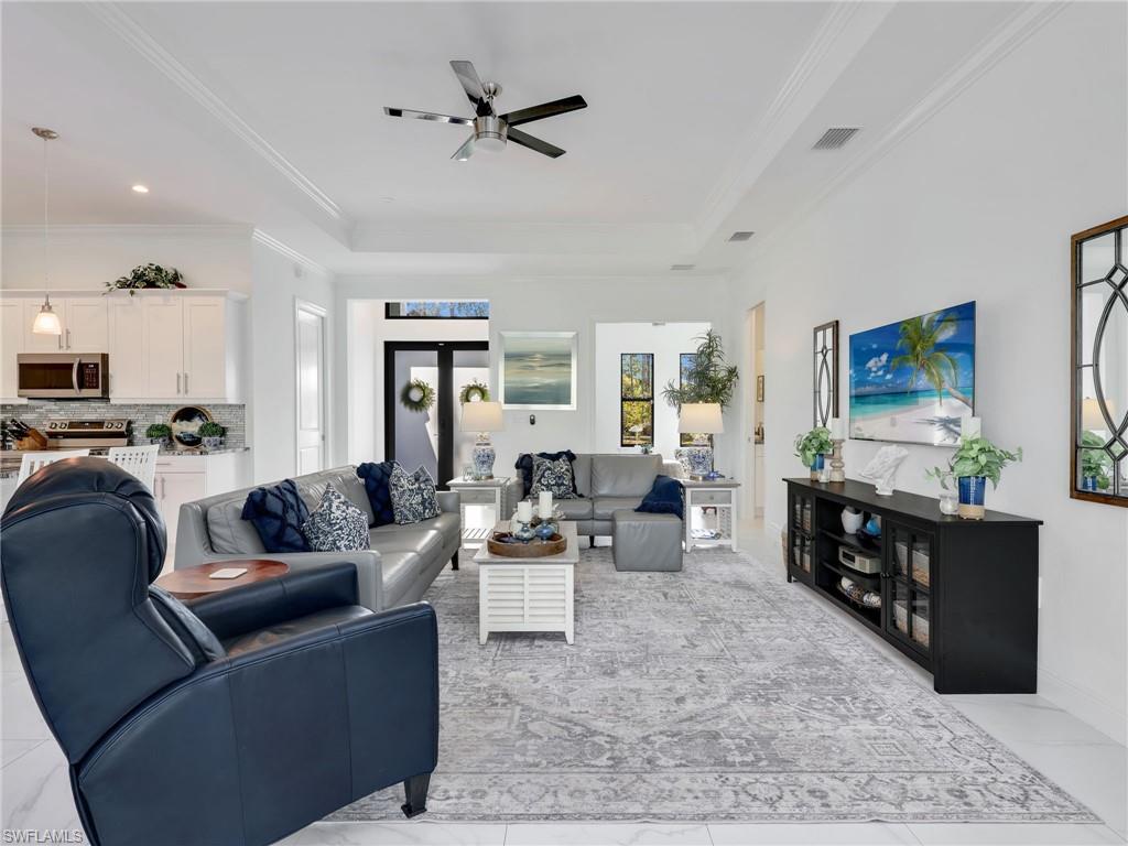 2007 22nd Avenue Northeast Naples, FL 34120 - Photo 14 of 47 Living Room With Tray Ceiling and Ceiling Fan, Kitchen, & Front Entry With Transom Window