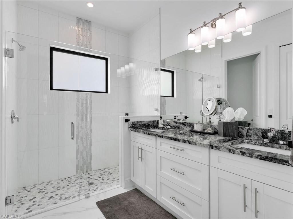 2007 22nd Avenue Northeast Naples, FL 34120 - Photo 19 of 47 En-Suite Primary Bathroom With Floor to Ceiling Tiled Shower, Tiled Shower Floor, Glass Enclosure, White Shaker Vanity With Drawers & Doors With Dual Sinks, & Quartz Counter