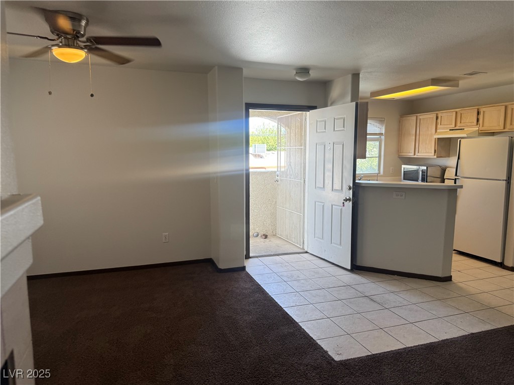 4500 West Lake Mead Boulevard, Unit 202 Las Vegas, NV 89108 - Photo 13 of 19 Kitchen featuring light tile patterned floors, freestanding refrigerator, light brown cabinets, a textured ceiling, and light colored carpet