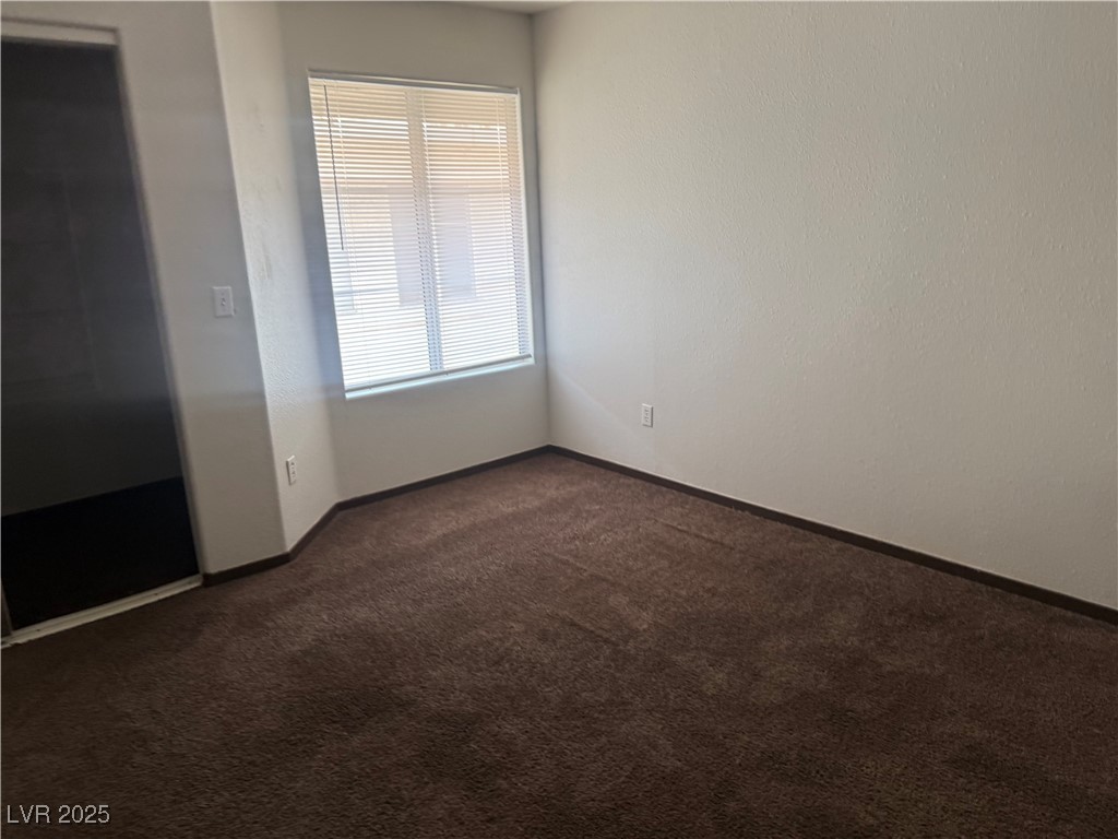 4500 West Lake Mead Boulevard, Unit 202 Las Vegas, NV 89108 - Photo 16 of 19 Empty room featuring dark carpet and baseboards
