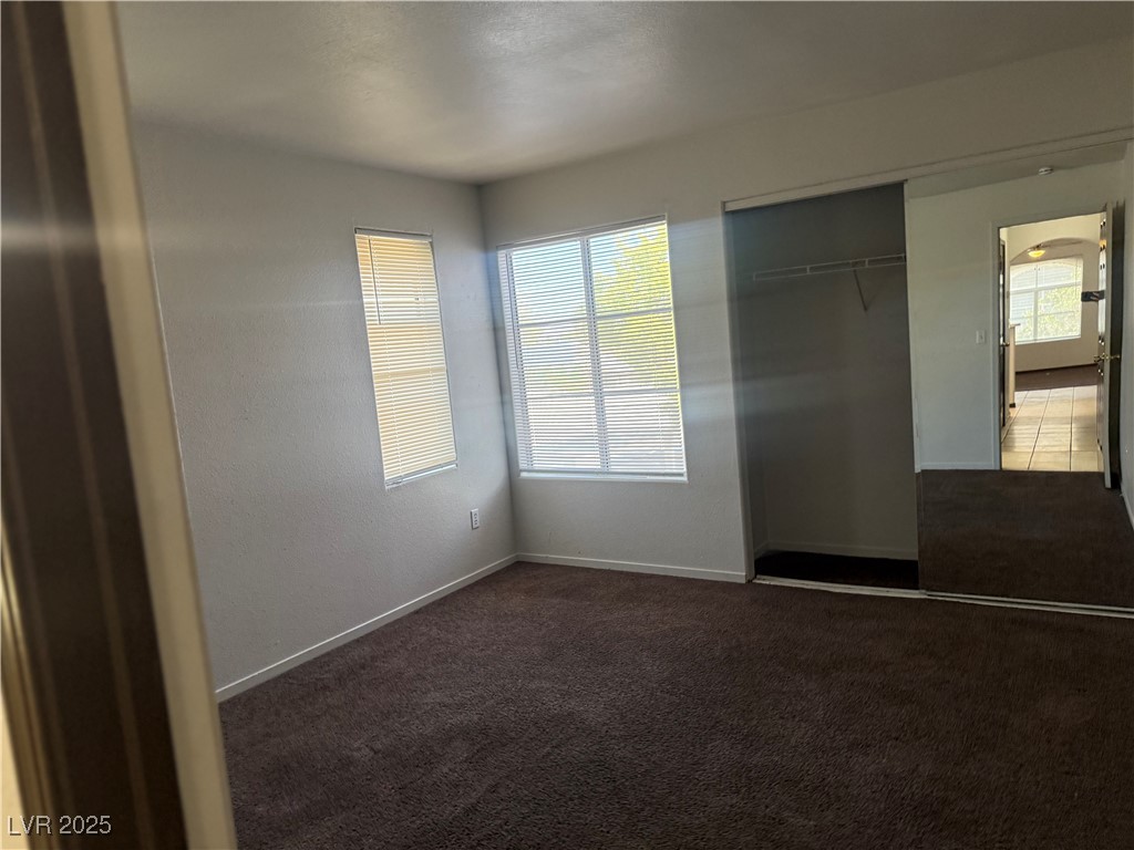 4500 West Lake Mead Boulevard, Unit 202 Las Vegas, NV 89108 - Photo 5 of 19 Unfurnished bedroom with multiple windows, dark carpet, a closet, and arched walkways