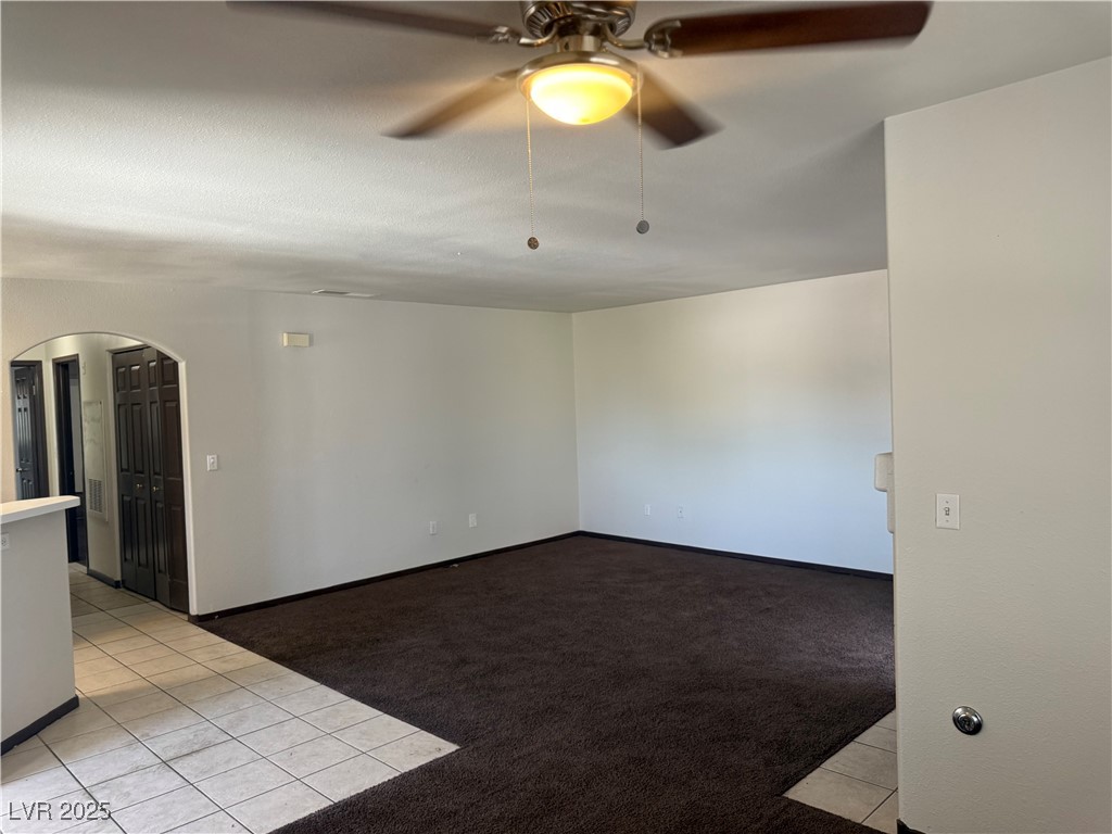 4500 West Lake Mead Boulevard, Unit 202 Las Vegas, NV 89108 - Photo 8 of 19 Empty room featuring light tile patterned flooring, light colored carpet, arched walkways, and a ceiling fan