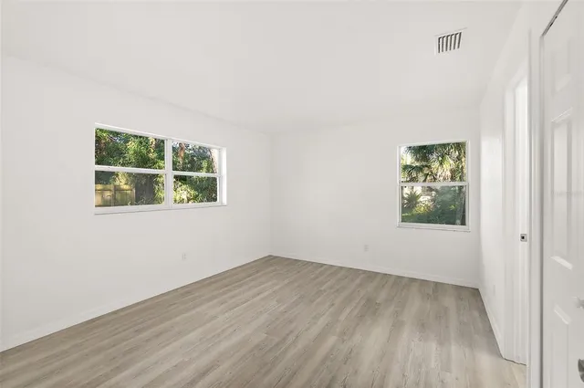 an empty room with wooden floor and window
