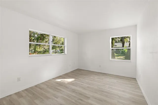 an empty room with wooden floor and window