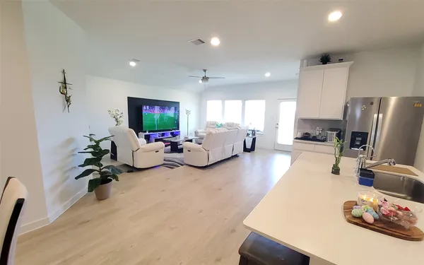 a kitchen with stainless steel appliances kitchen island granite countertop a sink a stove a refrigerator cabinets and a dining table with wooden floor