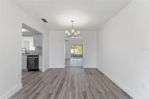 a view of empty room with wooden floor and kitchen