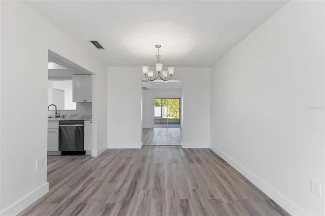 a view of empty room with wooden floor and kitchen