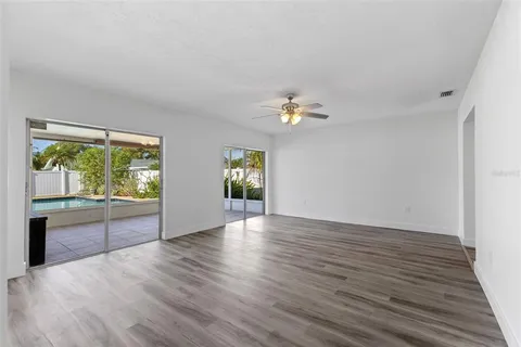 a view of an empty room with a window and wooden floor