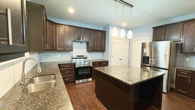 a kitchen with stainless steel appliances granite countertop a refrigerator stove microwave and sink