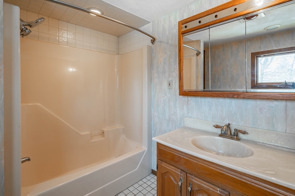 34 Summer Street Saugus, MA 01906 - Photo 26 of 35 a bathroom with a granite countertop sink a mirror and a bathtub