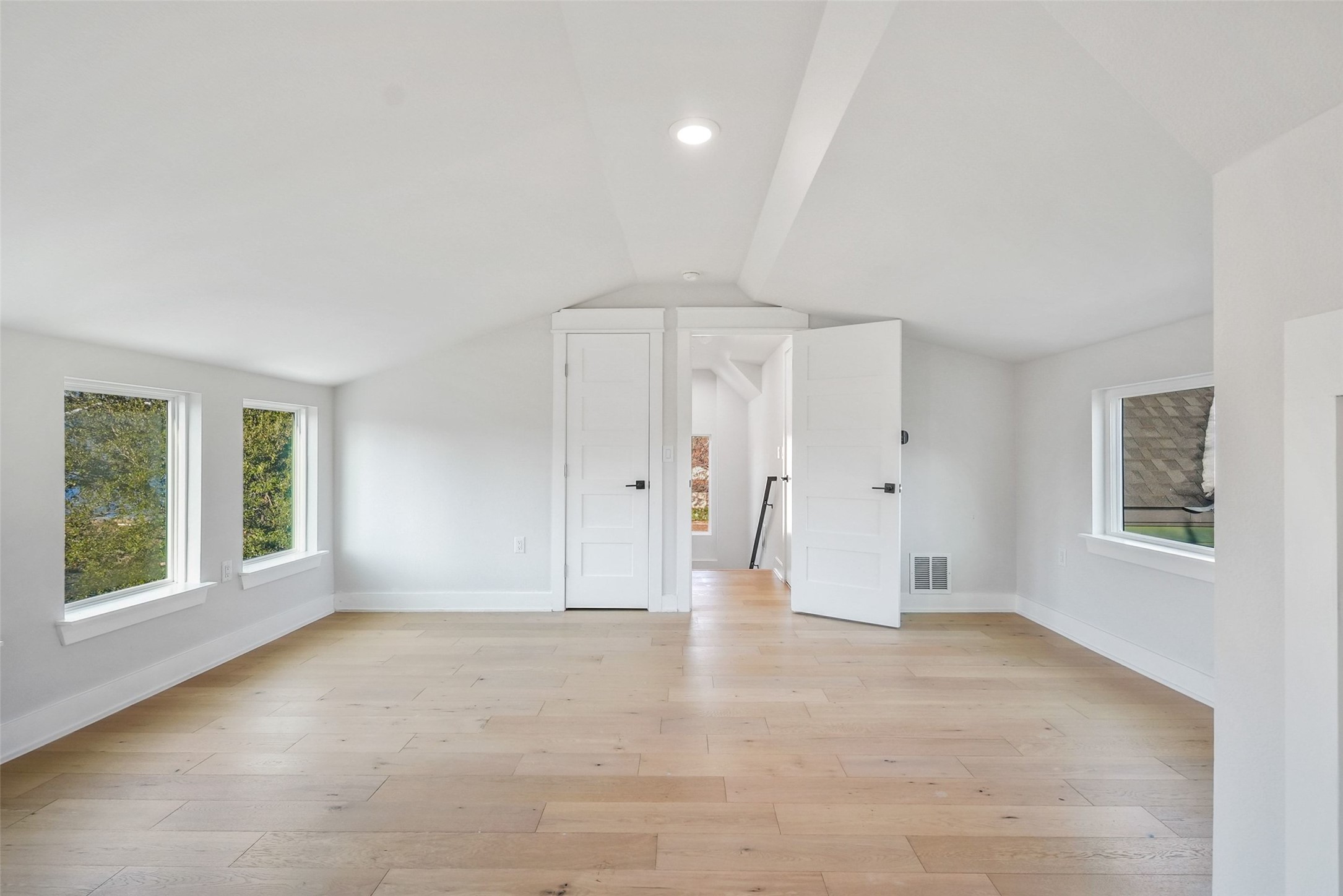 5109 Stone Gate Drive, Unit 2 Austin, TX 78721 - Photo 26 of 36 Spacious room featuring light wood-finish flooring, white walls, and a vaulted ceiling with recessed lighting