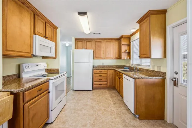 a kitchen with a refrigerator a stove a sink dishwasher and wooden cabinets with wooden floor