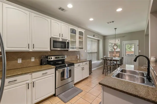 a kitchen with stainless steel appliances granite countertop a stove a sink and a microwave