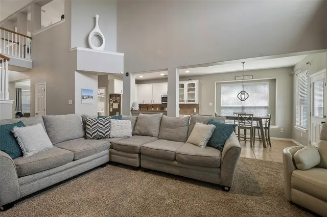 a living room with furniture kitchen view and a chandelier