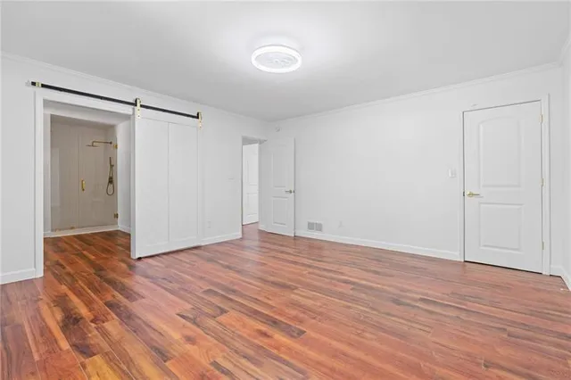 a view of an empty room with wooden floor and closet