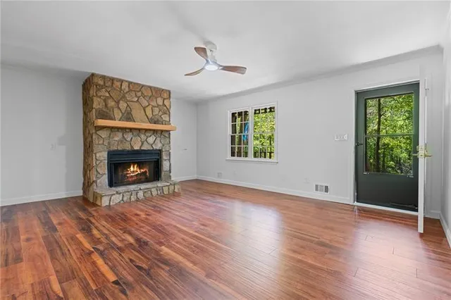 an empty room with windows a fireplace and wooden floor