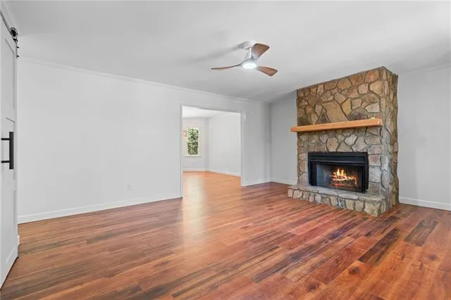 a view of an empty room with wooden floor fireplace and a window