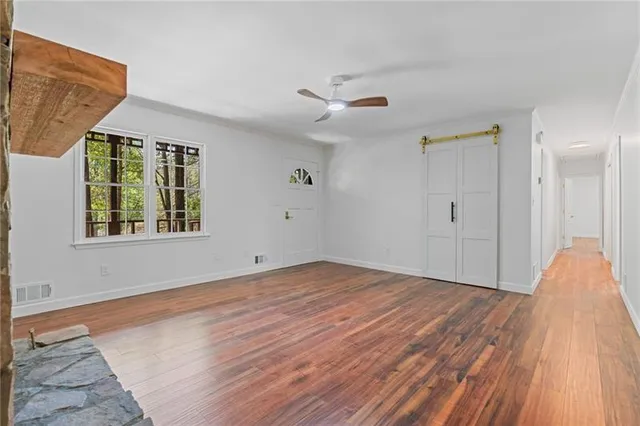 a view of an empty room with wooden floor and a window