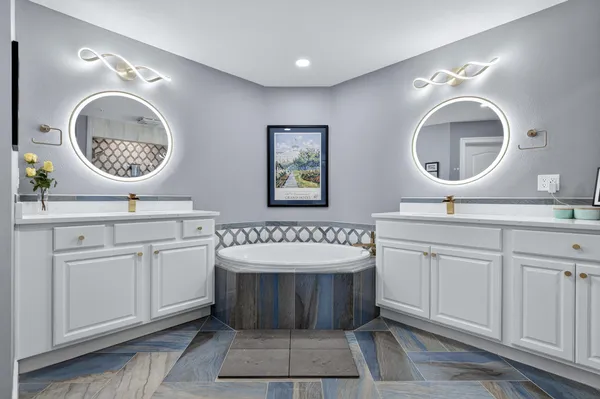 a bathroom with a double vanity sink mirror and bathtub
