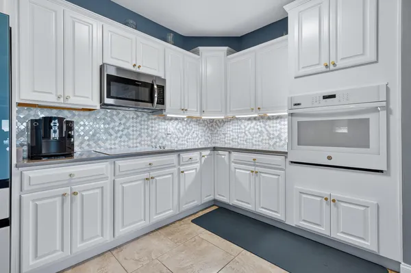 a kitchen with white cabinets and white appliances
