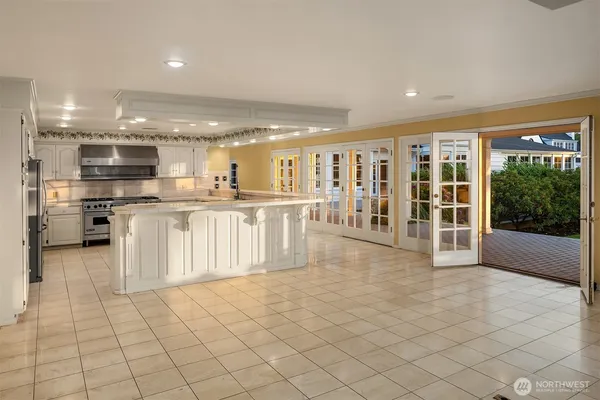 a large white kitchen with a large window and stainless steel appliances