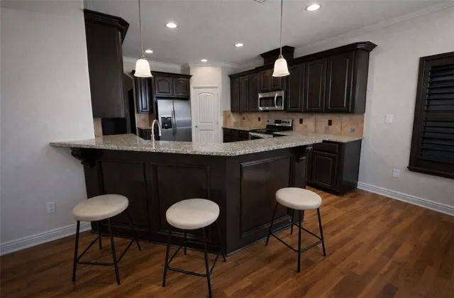 a kitchen with stainless steel appliances a sink cabinets and wooden floor