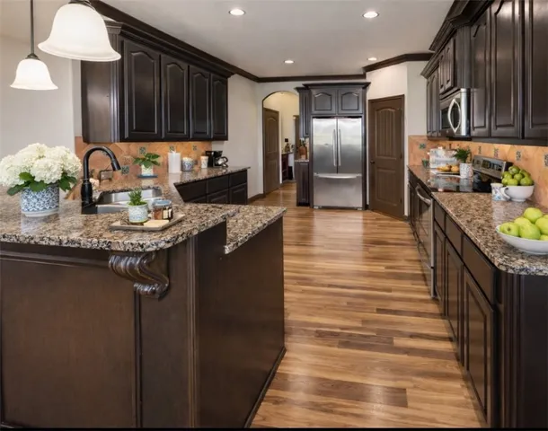 a kitchen with stainless steel appliances granite countertop a sink stove and refrigerator