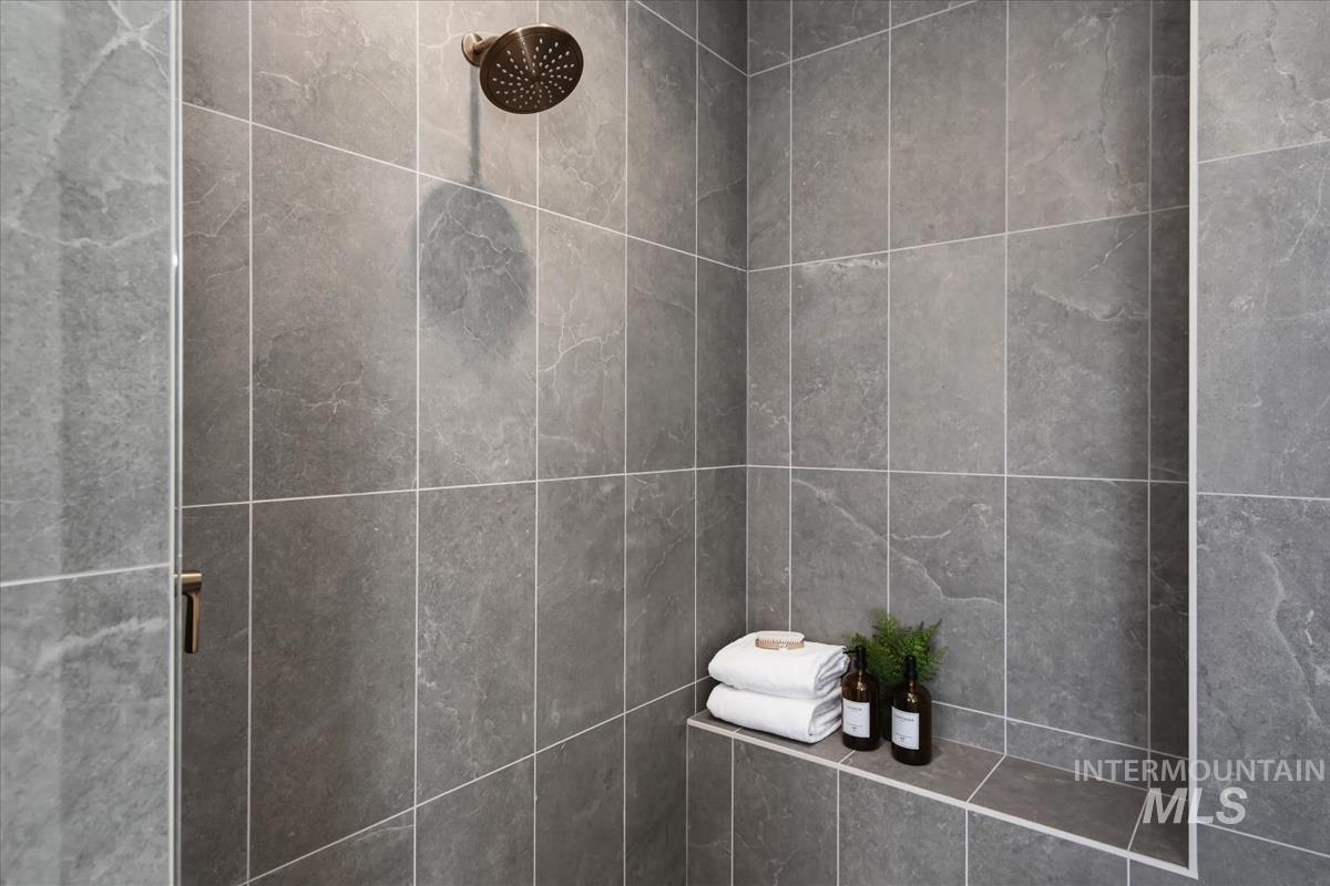 7615 Brown Way Eagle, ID 83714 - Photo 30 of 43 Shower enclosure with large format grey stone-look tiles, a built-in shower niche, and a bronze finish showerhead