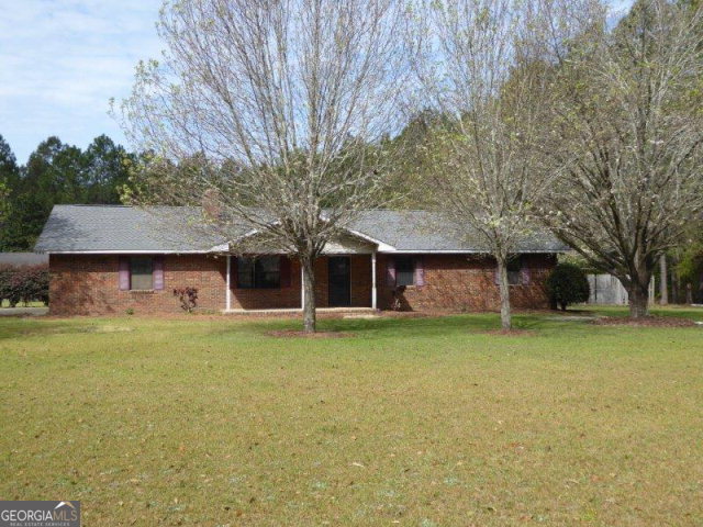 a front view of a house with a garden and trees
