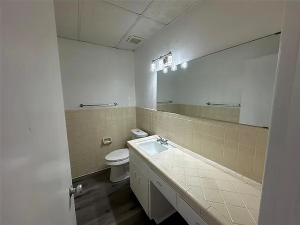 a bathroom with a granite countertop sink a toilet and a mirror