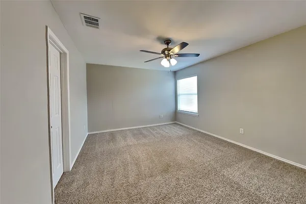 an empty room with windows and fan