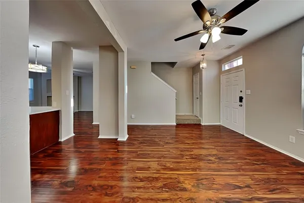 a view of an empty room with wooden floor and a ceiling fan